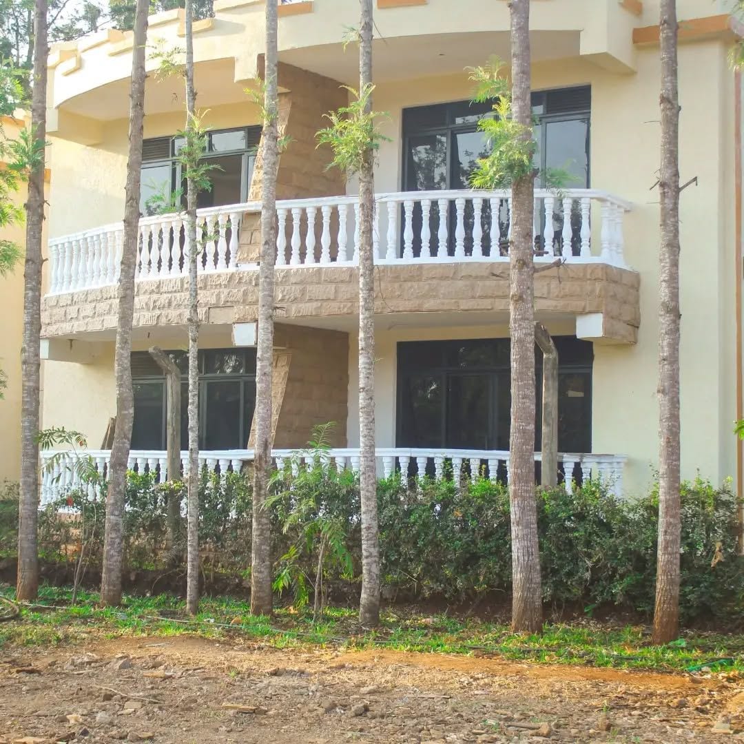 Un edificio de varios pisos con balcones, rodeado de árboles.