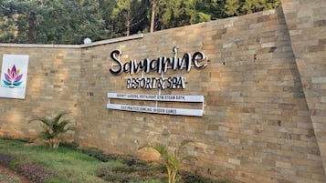 A sign for Samarine Resort & Spa with amenities listed including serenity gardens, restaurant, gym, steam bath, golf practice, bowling, and indoor games.