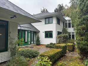 Ein zweistöckiges Haus mit Vordergarten, einem kleinen Baum und einem Weg.