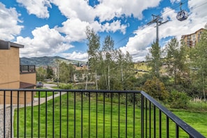 A residential area with a grassy lawn, a black metal fence, and a cable car in the background. - Ski-In/Out Gondola Views | Fireside & Hot Tubs (Steamboat Springs)