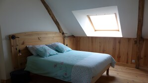Una camera da letto con soffitto spiovente, una finestra a lucernario, una struttura letto in legno e un comodino.
