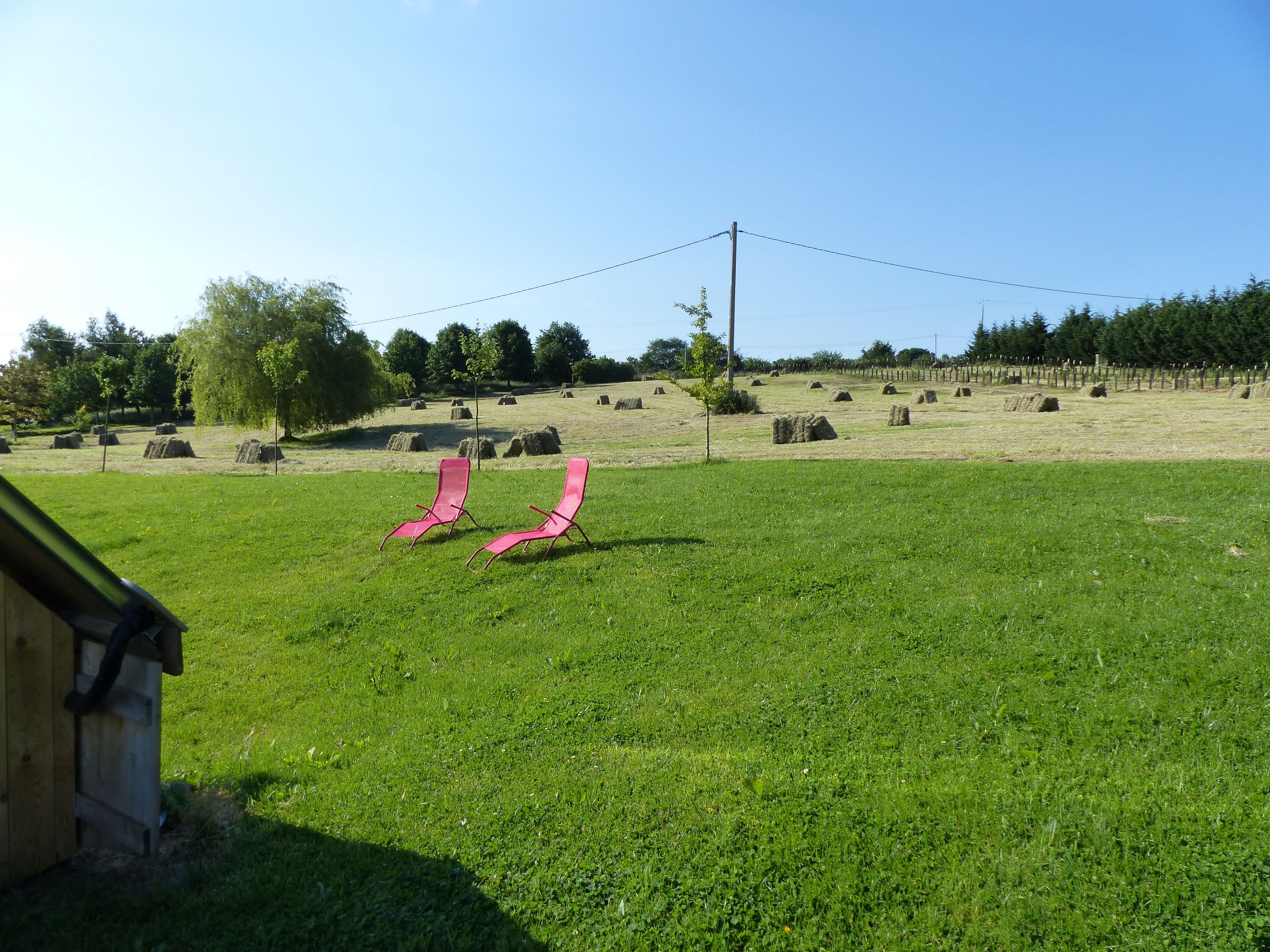 A grassy field with hay bales and a wooden structure in the foreground.
