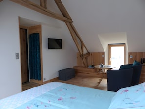 Un dormitorio con cama, televisor, una mesita y una escalera que sube a un nivel superior.