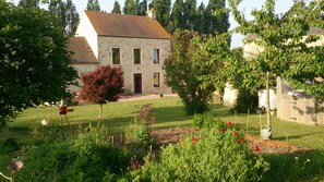 A stone house with a sloped roof, surrounded by a well-maintained garden with various plants and a small pond. - Bed and Breakfast 'Chambre D'hôtes Bois De Rose' with Private Garden and Wi-Fi (La Hoguette)