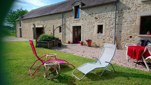 A stone building with a paved patio, outdoor seating, and potted plants. - Bed and Breakfast 'Chambre D'hôtes Bois De Rose' with Private Garden and Wi-Fi (La Hoguette)