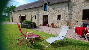 A stone building with a paved patio, outdoor seating, and potted plants. - Bed and Breakfast 'Chambre D'hôtes Bois De Rose' with Private Garden and Wi-Fi (La Hoguette)
