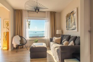 A modern living room with a view of the sea, a sofa set, a chair, and a lamp. - The Casa da Fonteseca Wake up facing the sea (Ribeira)