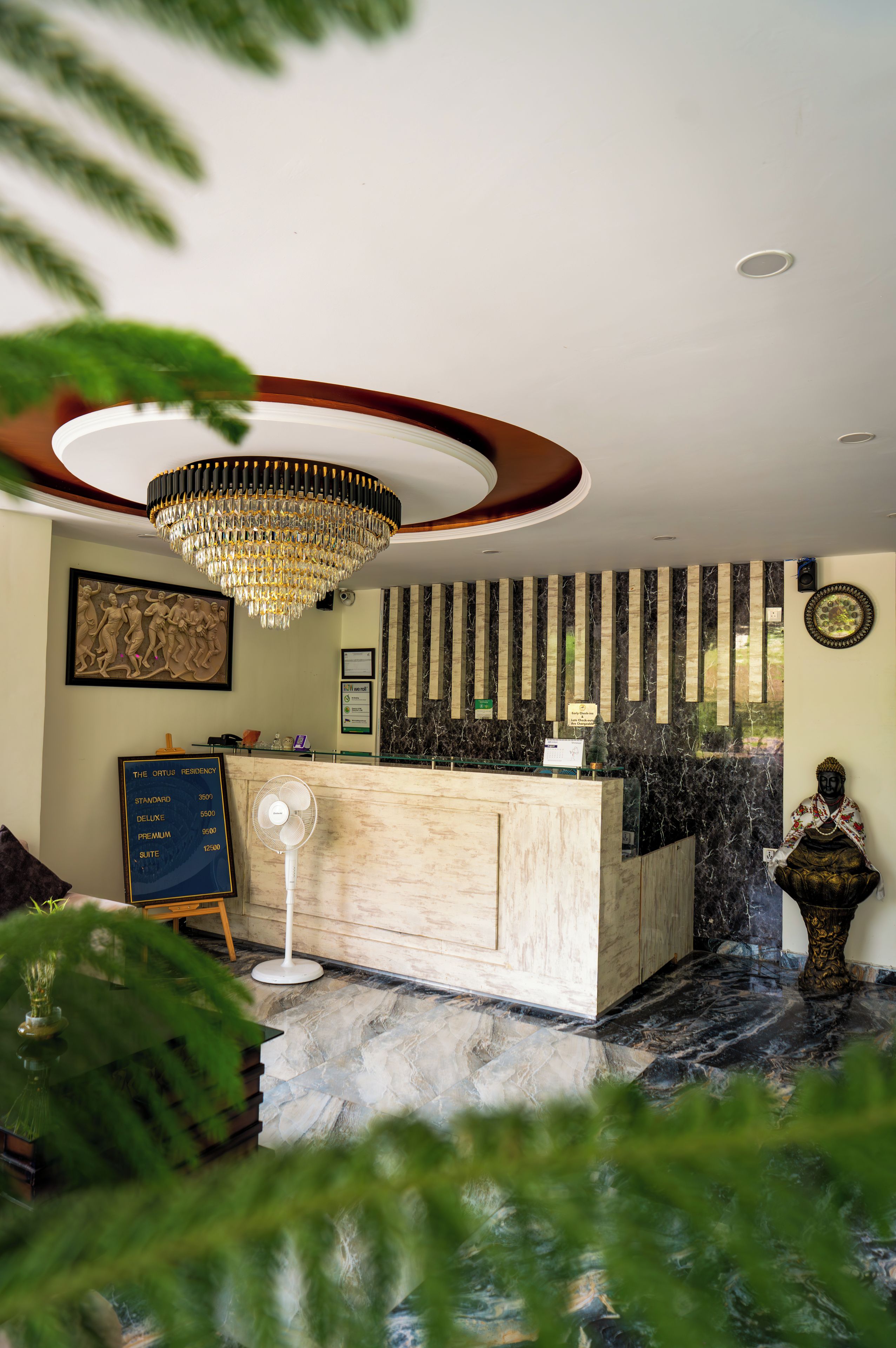 A reception desk with a marble counter, a chandelier, and a Buddha statue.
