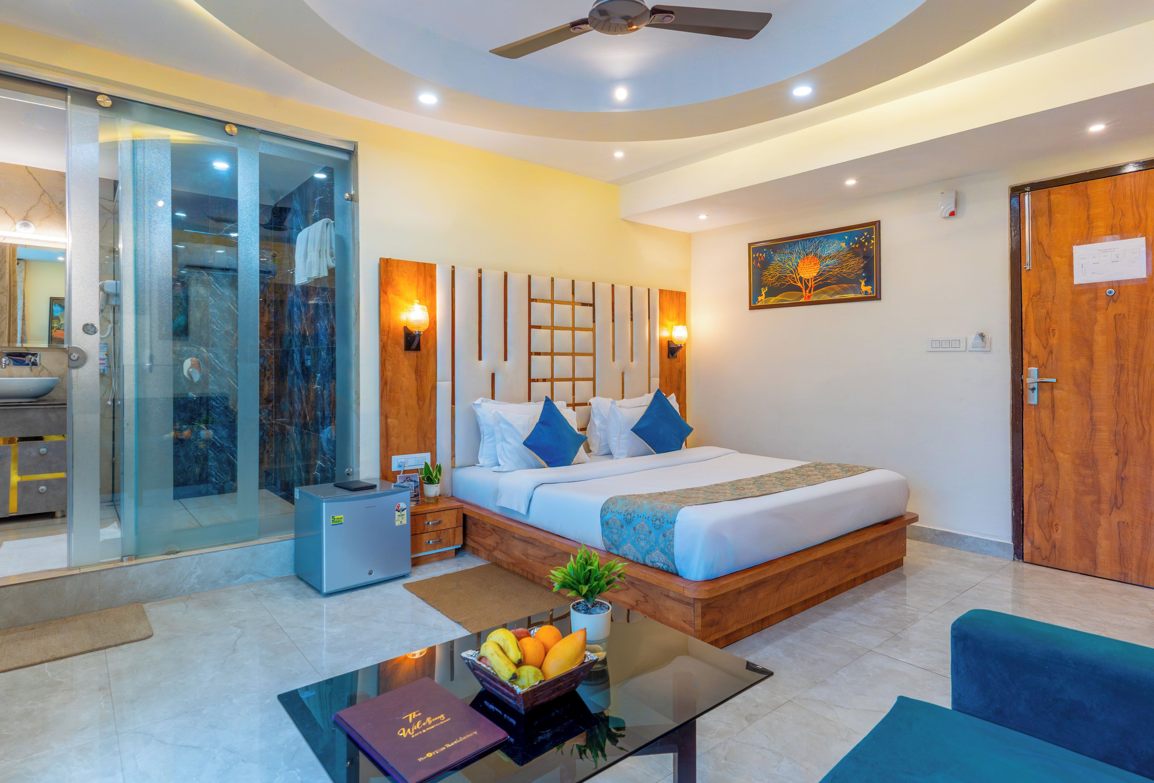 A modern hotel room with a bed, bedside table, and a glass shower enclosure.