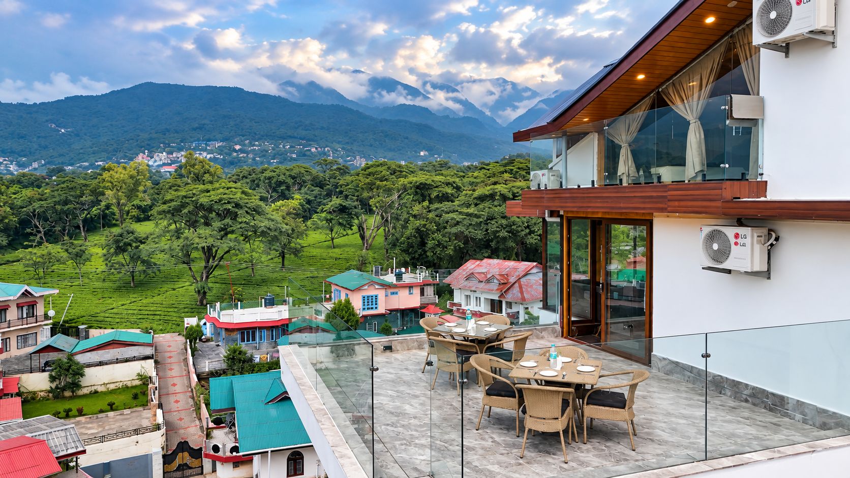 A terrace with outdoor seating, overlooking a mountainous landscape with houses in the background.