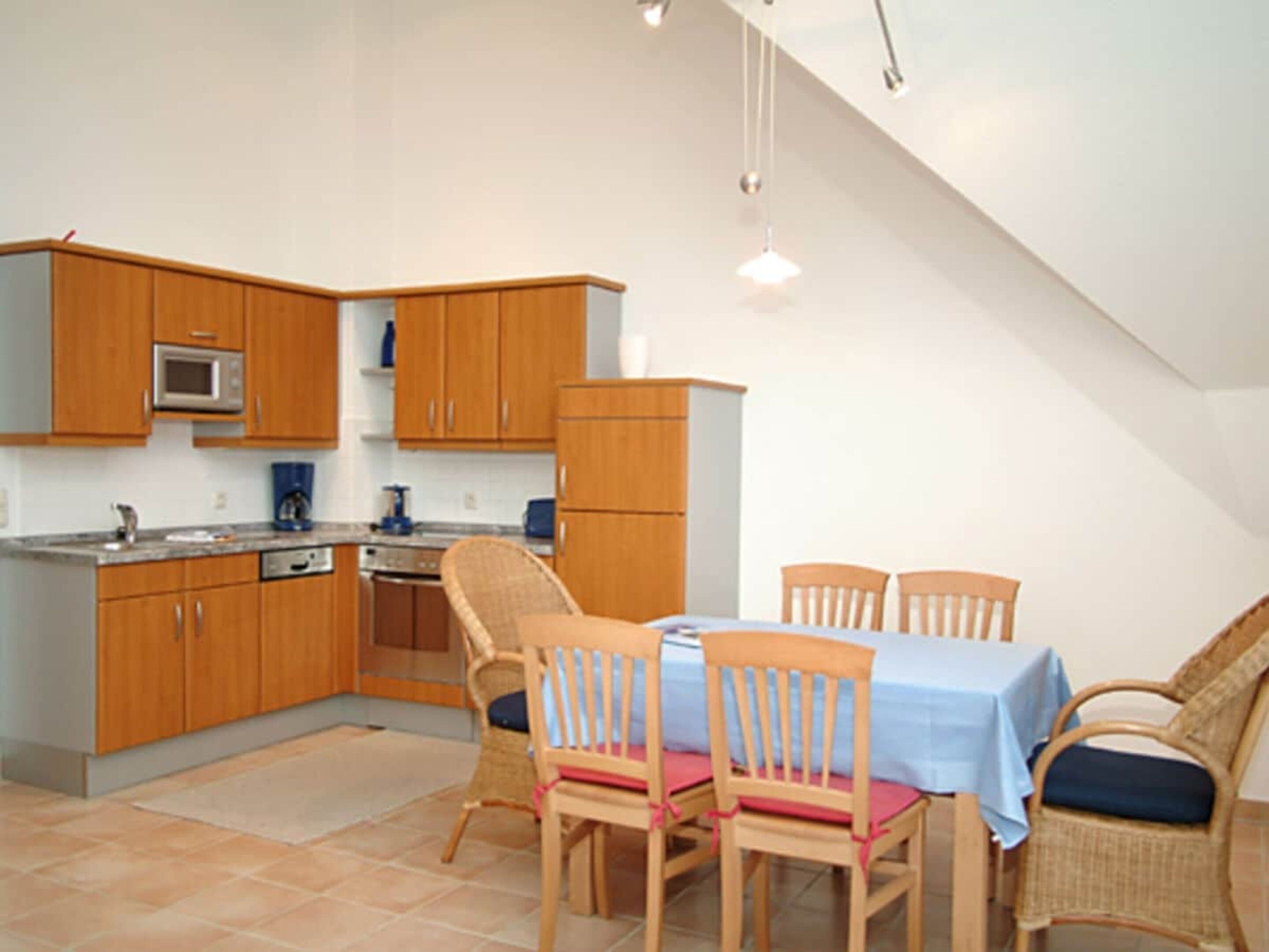 A kitchen with wooden cabinets, a microwave, and a dining area with a table and chairs.
