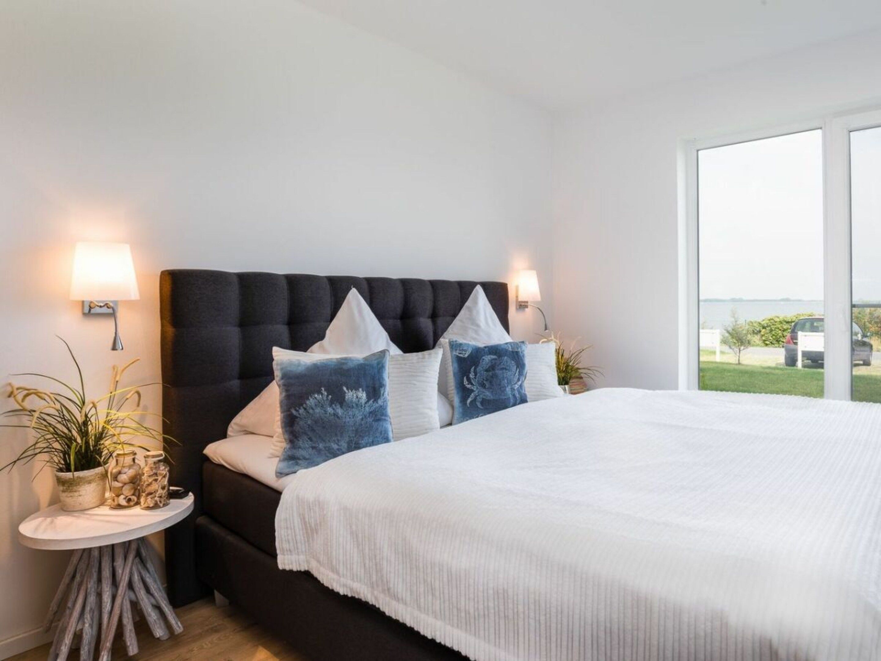 Quarto com uma cama grande, duas mesas de cabeceira e vista para o exterior.