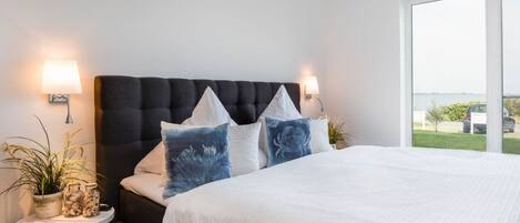 Un dormitorio con una cama grande, dos mesitas de noche y vistas al exterior.