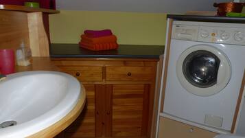 Une petite salle de bain comprenant un lavabo, des toilettes et un lave-linge.