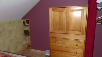 Une pièce avec une armoire en bois, un mur violet et un rideau rouge.