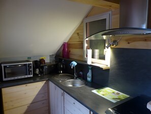 Cocina compacta equipada con microondas, tetera, fregadero y estufa.