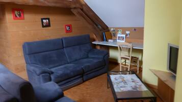 Un salon chaleureux avec un canapé bleu, un plafond en bois et une petite table sur laquelle se trouvent des papiers.