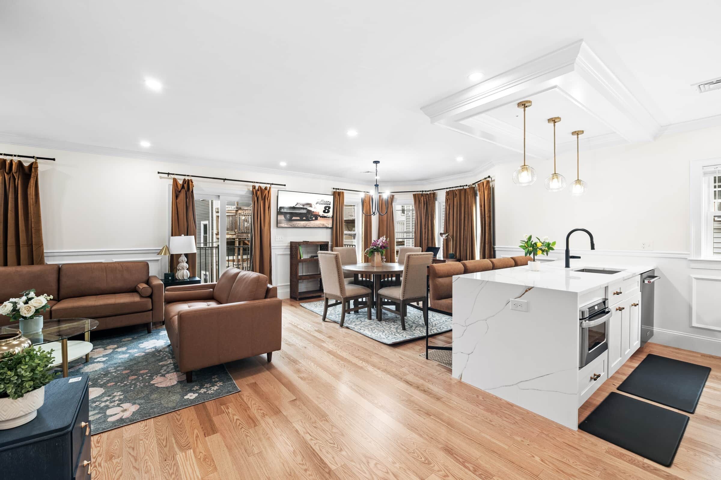 Una sala de estar moderna con sofá, comedor y cocina con isla integrada.
