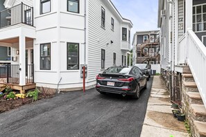 A narrow street with residential buildings, a parked car, and a fire hydrant. - Designer Condo in Jamaica Plain | Steps to Forest Hills (Boston)