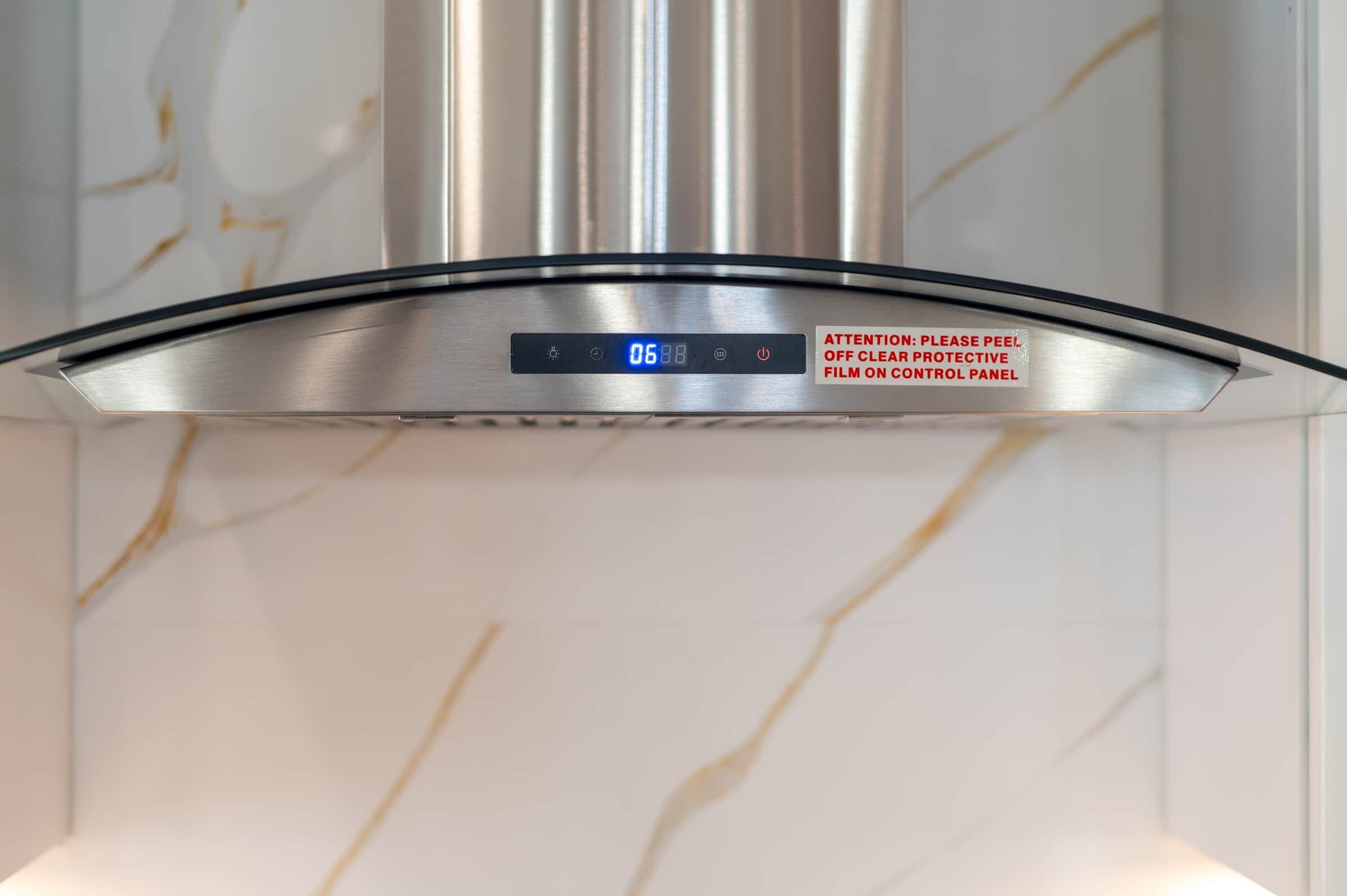 A stainless steel range hood with a digital display and a warning label.
