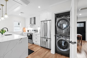 Een moderne keuken met een inbouwoven, een roestvrijstalen koelkast en een wasmachine met dubbele deur.