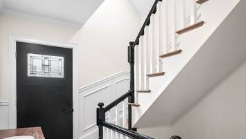 A modern interior with a staircase, wooden flooring, a dining table, and a black door.