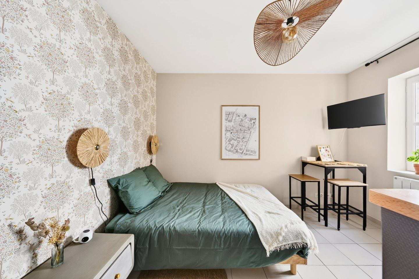 Un dormitorio con cama, escritorio, silla, televisión y una pared con un mapa.