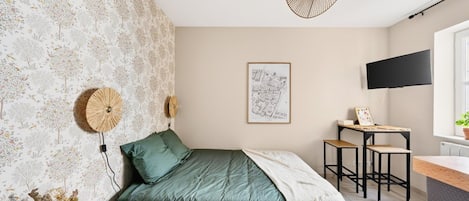 Un dormitorio con cama, escritorio, silla, televisión y una pared con un mapa.