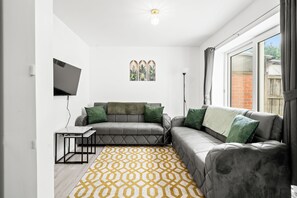 A modern living room with a grey sofa, a small table, and a patterned rug.