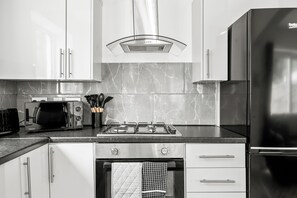 A modern kitchen with white cabinets, a built-in stove, and a stainless steel refrigerator.