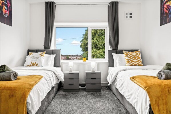 A bedroom with two beds, a window with a view, and a radiator.