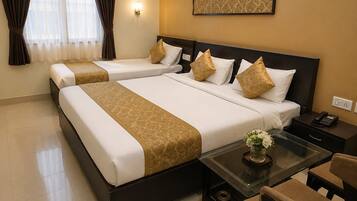 A hotel room with two beds, a nightstand with a phone, a small table with a vase, and a chair.