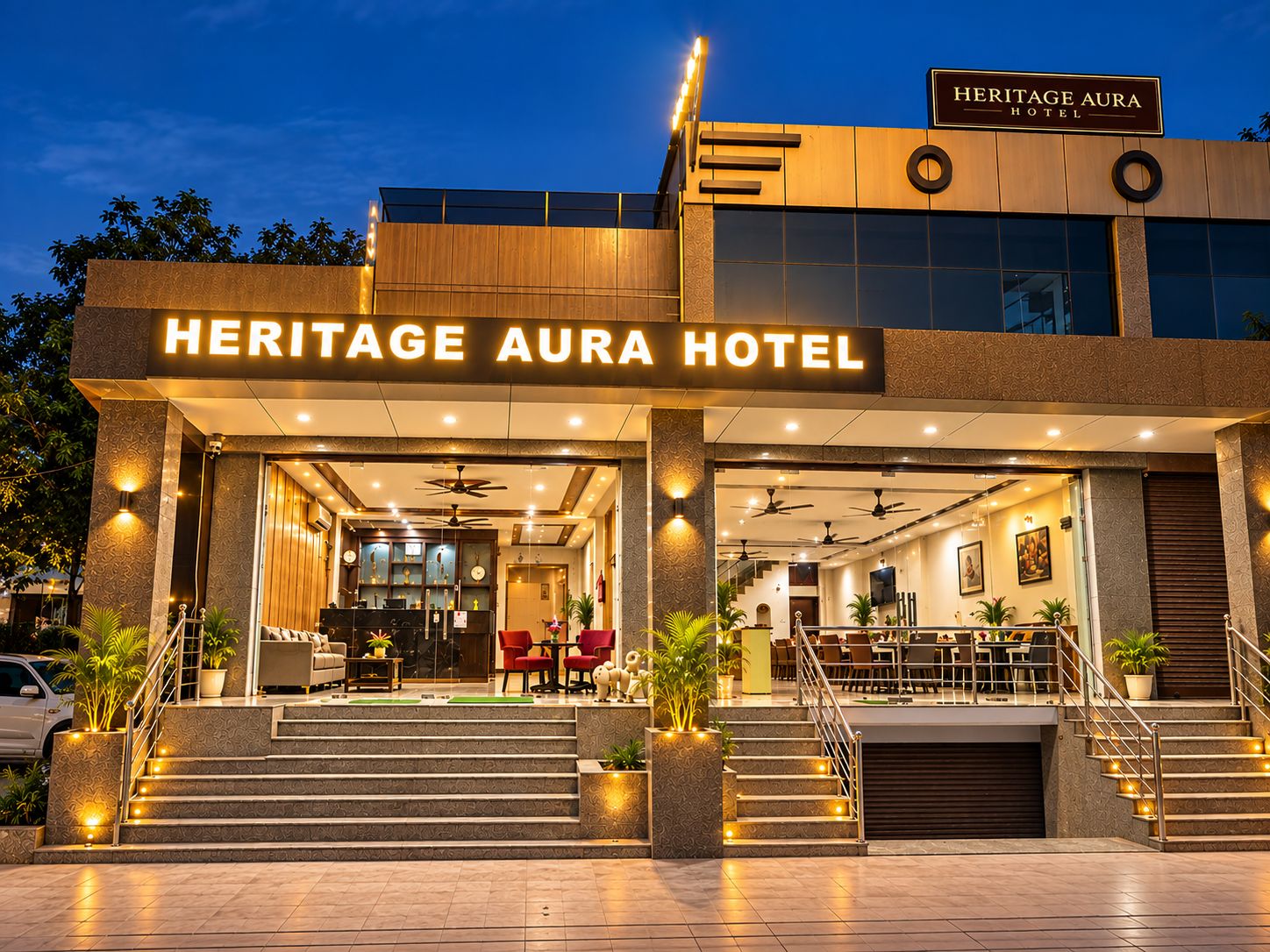 Exterior do Heritage Aura Hotel, com design moderno, destacando uma entrada imponente, uma área de recepção e uma escadaria que leva ao lobby.