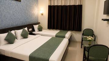 Quarto de hotel com duas camas, uma cadeira, uma mesa, um quadro na parede e uma televisão.