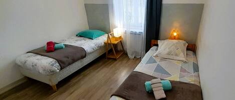 A room with two beds, a small table, and a chair.