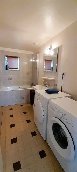 A compact bathroom with a sink, mirror, and two washing machines. - La Forge- Gite 4 pers- face au canal du Berry- Wifi (Thénioux)