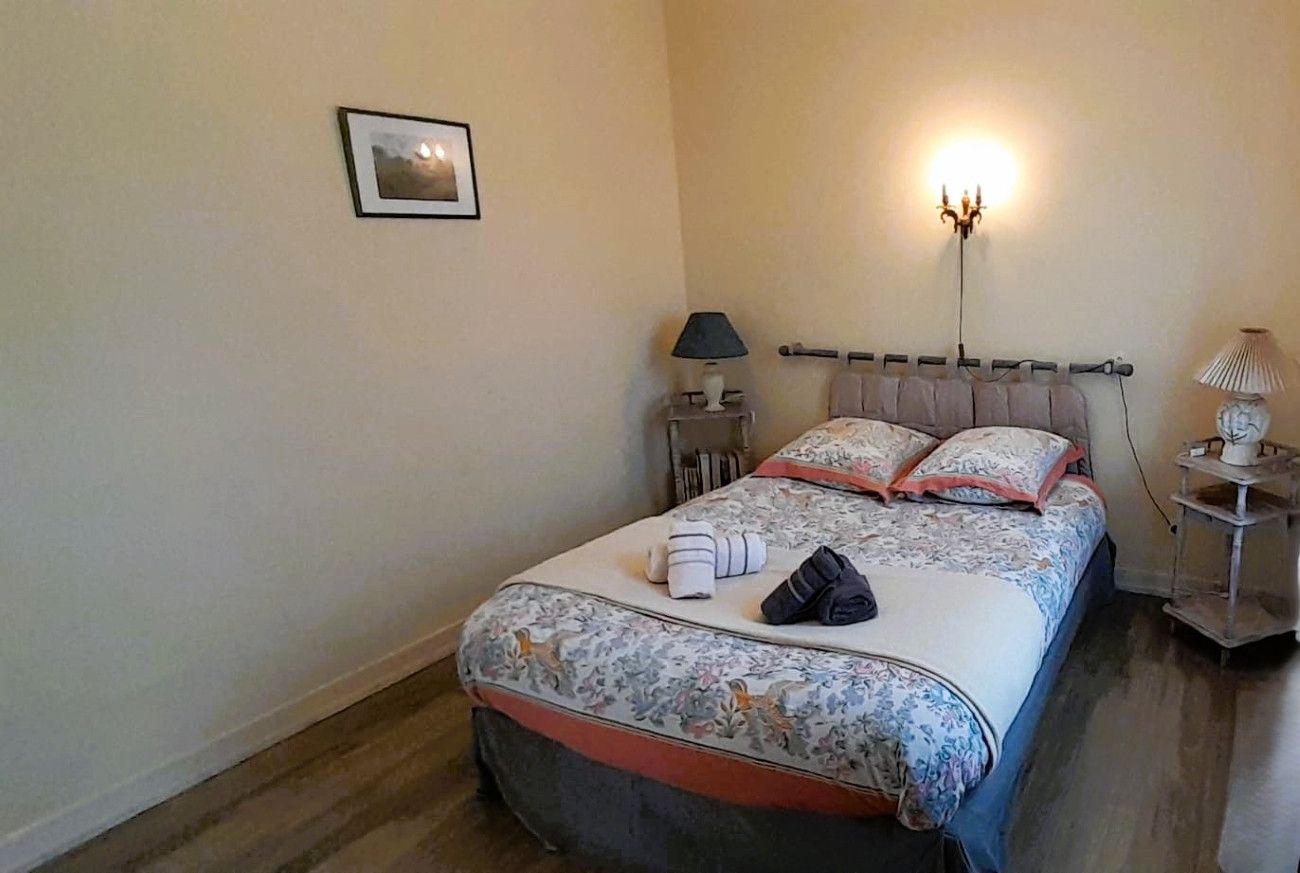 Una camera da letto con un letto, lampade sui comodini e un punto luce a parete.