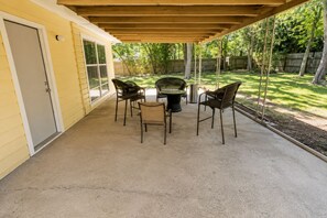 An outdoor patio with a covered seating area, a grill, and a concrete floor.