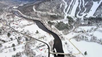A river winding through a snowy landscape with a bridge and buildings on the riverbank.