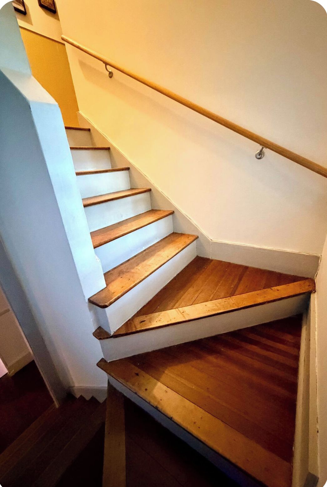 Eine Treppe mit Holzdielen und einem weißen Geländer.