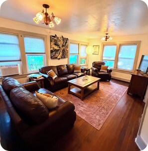 A living room with a leather sofa set, a coffee table, and a chandelier.