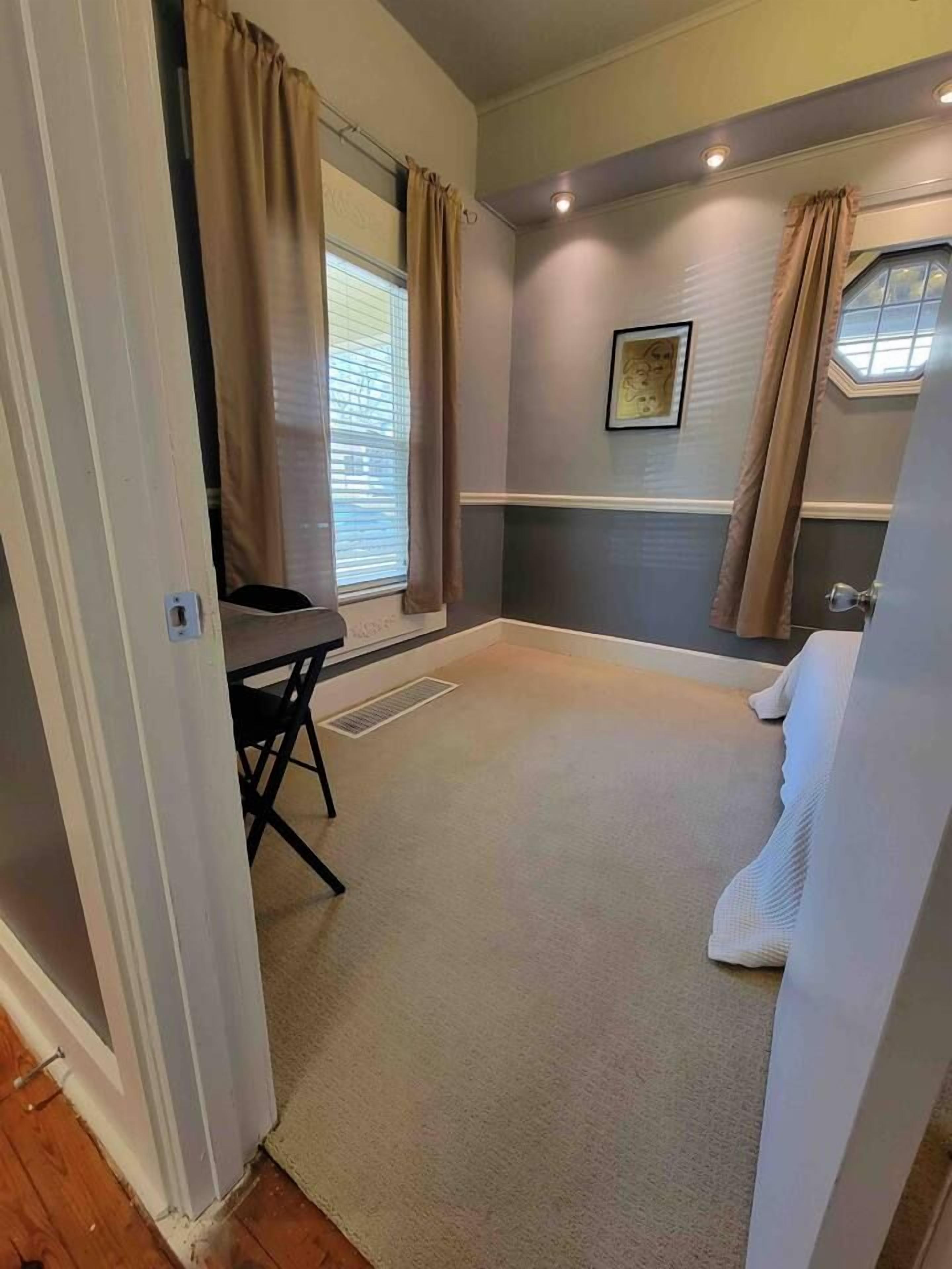 Une pièce avec une fenêtre, un radiateur, une chaise et un lit.