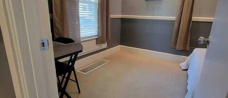 A room with a window, a radiator, a chair, and a bed.
