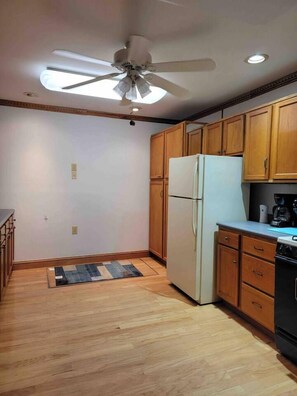 A kitchen with wooden cabinets, a refrigerator, a stove, and a ceiling fan. - Cozy 2BR Indianapolis Home | Pet Friendly (Indianapolis)