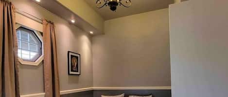 Un dormitorio con una cama, un candelabro, una ventana con cortinas y una puerta.