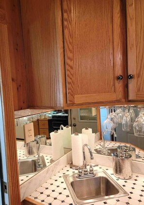 A kitchen with wooden cabinets, a stainless steel sink, and a tiled backsplash. - Cozy 2BR Indianapolis Home | Pet Friendly (Indianapolis)