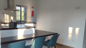 A modern kitchen with a central island, two blue chairs, and a window with a view.