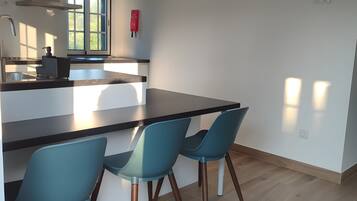 Une cuisine moderne avec un îlot central, deux chaises bleues et une fenêtre donnant sur un beau paysage.