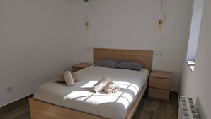 A modern bedroom with a wooden bed, two bedside tables, and a window.