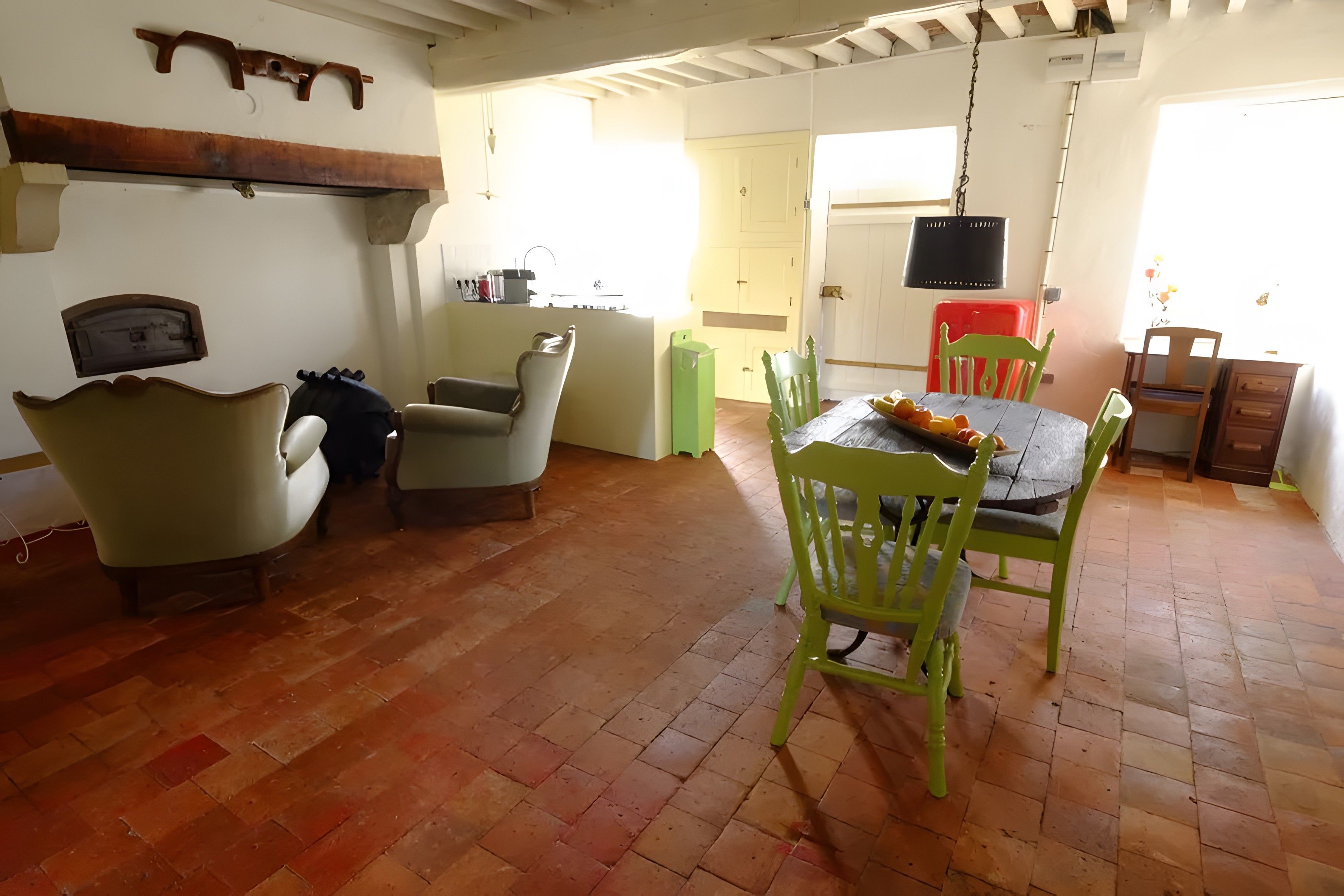 Uma sala de jantar com mesa e cadeiras, uma cozinha com pia e armários, e uma sala de estar com sofá e cadeiras.